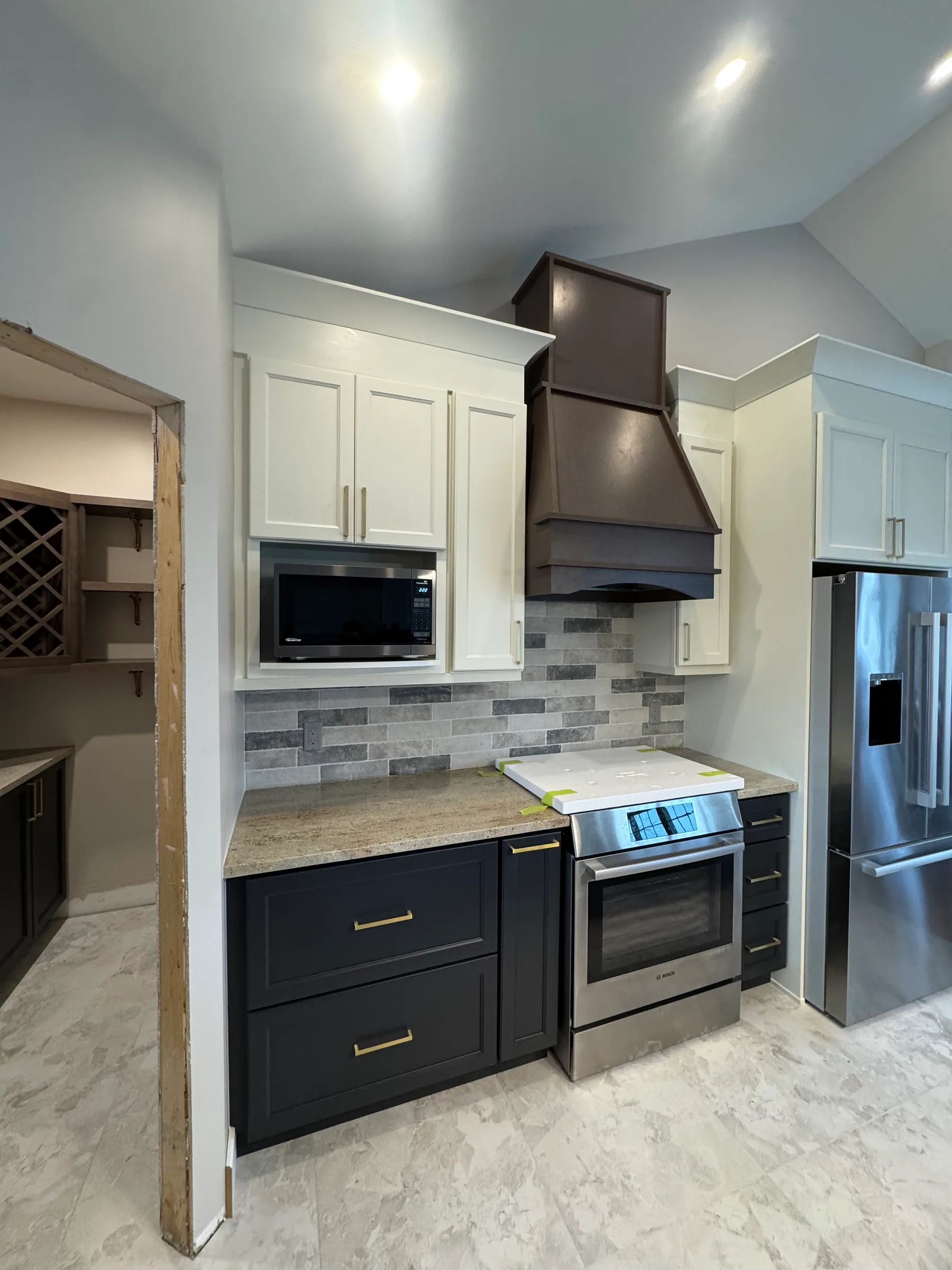 Two-tone kitchen cabinetry with a custom dark wood vent hood, Smiths Falls